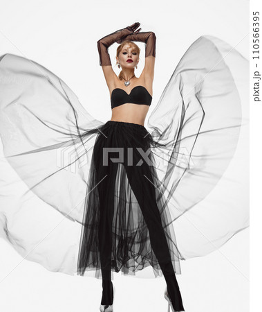 Beautiful woman in a transparent black skirt, bodice and neck decoration posing on a white background 110566395