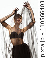 Beautiful woman in a transparent black skirt, bodice and neck decoration posing on a white background 110566403