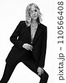A beautiful woman with loose hair, in a jacket and beads, poses in the studio 110566408