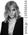 A beautiful woman with loose hair, in a jacket and beads, poses in the studio 110566414