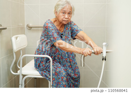 Asian elderly old woman patient use toilet support rail in bathroom, handrail safety grab bar, security in nursing hospital. 110568041