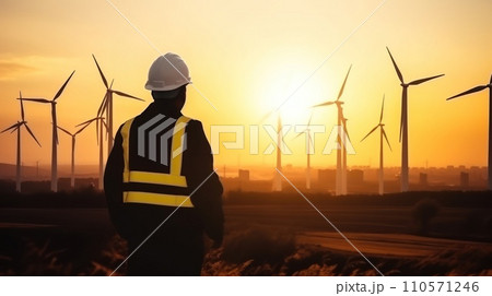 young male engineer holding laptop computer planning and working for the energy industry and standing beside a wind turbines farm power station at sunset time young male engineer holding laptop computer planning and working for the energy industry and standing beside a wind turbines farm power station at sunset time 110571246
