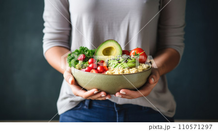 A woman in a t-shirt and jeans standing and holding a vegan food 110571297