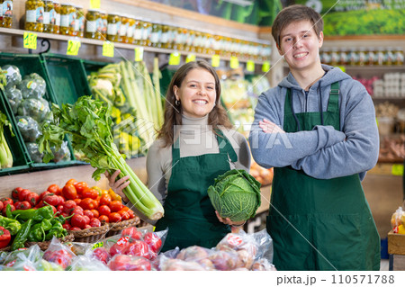 Young male and female sellers posing in grocery market holding vegetables in hands Young male and female sellers posing in grocery market holding vegetables in hands 110571788
