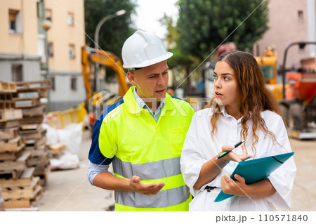 Man engineer and a young woman discuss a construction project while , taking important notes 110571840