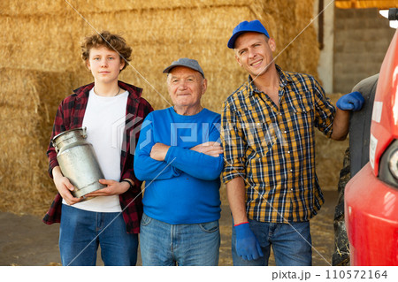 Various aged farmers standing inside hay bales storage 110572164