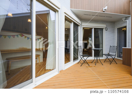 ウッドデッキとテーブルと椅子のある洋風建築 110574108