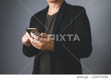 Businessman in suit standing sideways holding and touch smartphone. Businessman in suit standing sideways holding and touch smartphone. 110574266
