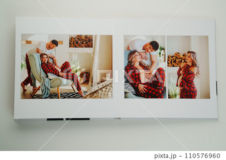 The pages of a photo book with color photos of a pregnant blonde and a man. The pages of a photo book with color photos of a pregnant blonde and a man. 110576960
