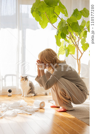 トイレットペーパーでいたずらをする猫を見て頭を抱える飼い主 110577280