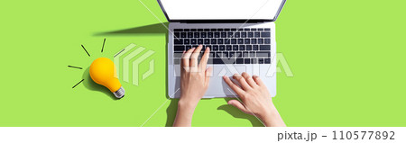 Person using a laptop computer and a light bulb 110577892