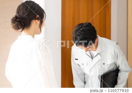お辞儀をする作業服姿の男性と見送りをする主婦 110577910