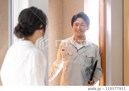 顧客の家に上がる作業服姿の男性業者と出迎える主婦（リフォーム・お邪魔します・アフターフォロー） 110577911