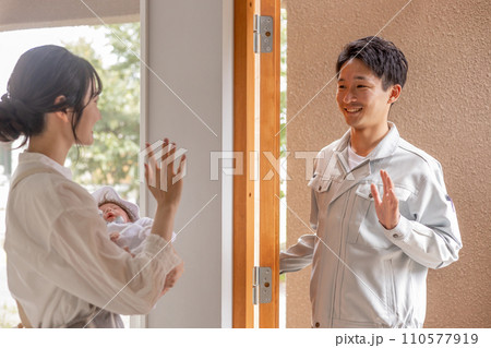 赤ん坊を抱っこしながら見送りをする女性（新婚夫婦・夫婦） 110577919