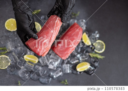 Chef holding piece of Fresh cooled tuna Fish fillet over pieces of ice 110578383