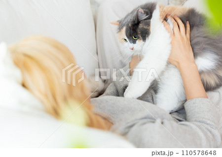 飼い主さんとソファーでくつろぐ猫 110578648