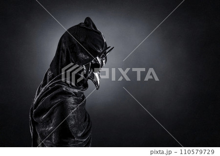Creepy figure with animal horned skull over dark misty background 110579729