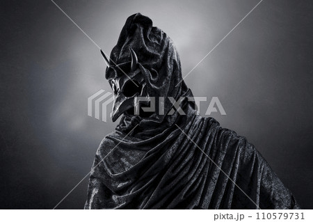 Creepy figure with animal horned skull over dark misty background 110579731