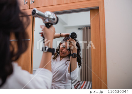 attractive girl wearing white bath robe using hair dryer 110580344
