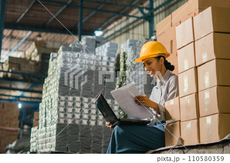 female factory worker sits using a laptop computer while working female factory worker sits using a laptop computer while working 110580359