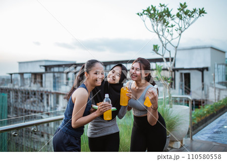 three young ladies chatting in sportswear holding a drink after exercise 110580558
