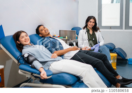 two patients lie down and a doctor smiles during blood transfusion two patients lie down and a doctor smiles during blood transfusion 110580658