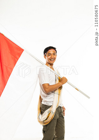 a handsome man standing bring a stick with indonesian flag and smiling 110580675
