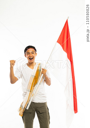 a young man standing bring a stick with indonesian flag and smiling 110580826