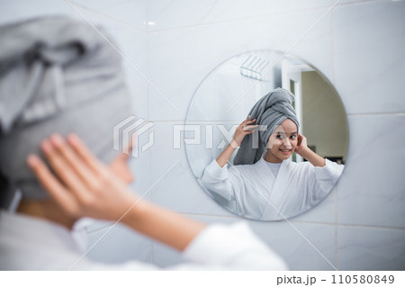 Asian girl wears a towel for hair while reflecting in the bathroom 110580849