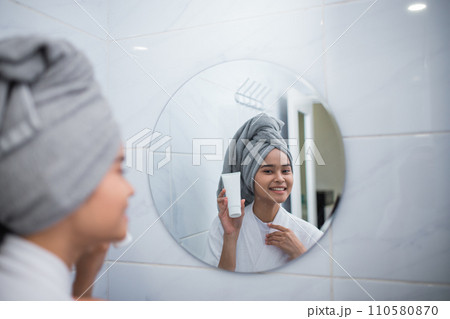 smiling girl with bathrobe seen from the reflection of the mirror 110580870
