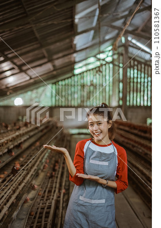 Asian female farmer with hands presenting something at chicken farm 110581367