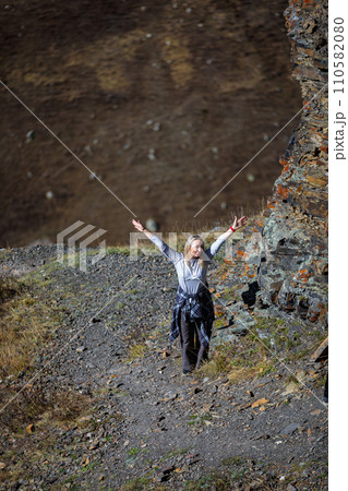 Happy girl standing on top of a mountain, enjoying the view, spreading her arms to the sides 110582080