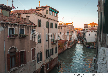 A serene view of a canal in Venice, Italy, with no gondolas or boats in sight. The predominant color of the buildings and the atmosphere are unspecified. A serene view of a canal in Venice, Italy, with no gondolas or boats in sight. The predominant color of the buildings and the atmosphere are unspecified. 110583976