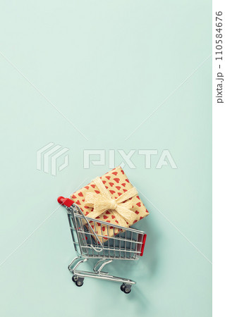 Valentine's Day composition, shopping trolley and gift box on blue background 110584676