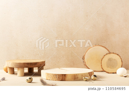 Empty round wooden podiums, quail eggs with green eucalyptus branches on a beige background. 110584695