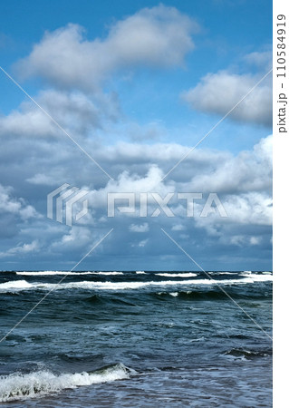The dark waves of the sea roll over the shore. 110584919