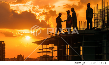 日の出時、建設現場で設計図を議論する建設チーム、夜明けの空に映えるシルエット。 日の出時、建設現場で設計図を議論する建設チーム、夜明けの空に映えるシルエット。 110586471