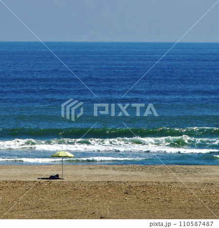海岸の波とパラソル 110587487