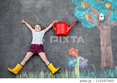 Cute little girl painting with colorful chalks apples harvest from apple tree on asphalt. Cute preschool child with having fun with chalk picture. Creative leisure for children, drawing and painting. Cute little girl painting with colorful chalks apples harvest from apple tree on asphalt. Cute preschool child with having fun with chalk picture. Creative leisure for children, drawing and painting. 110587905