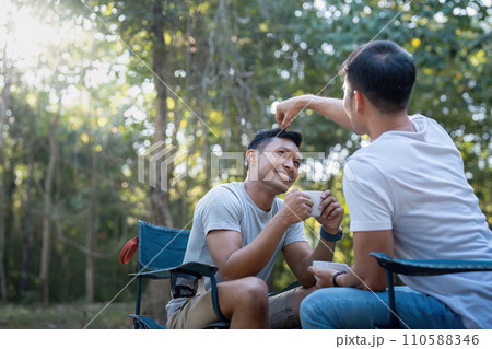 Male gay couple asian traveling with tent camping outdoor and various adventure lifestyle hiking active summer vacation. drinking coffee and talking together 110588346