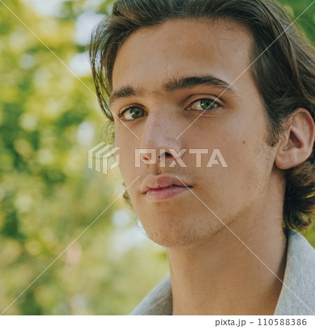 Closeup portrait of handsome young man at the park in summer. Caucasian teenager looks to the camera, outdoor portrait. Handsome face of a male model with brown hair at the city. One person Closeup portrait of handsome young man at the park in summer. Caucasian teenager looks to the camera, outdoor portrait. Handsome face of a male model with brown hair at the city. One person 110588386