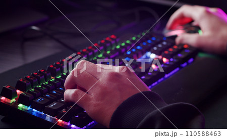 Male hands is typing on the computer keyboard, close up view. Man working on the pc computer. Human hands typing on the colourful gaming keyboard. Fingers typing on the led rgb keyboard. Male hands is typing on the computer keyboard, close up view. Man working on the pc computer. Human hands typing on the colourful gaming keyboard. Fingers typing on the led rgb keyboard. 110588463