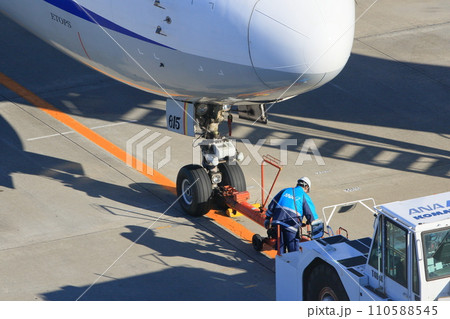 トーイングカーをセットする地上誘導員　羽田空港のマーシャリング　グランドハンドリング 110588545