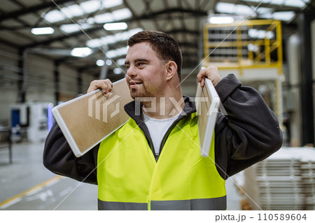 Portrait of young man with Down syndrome working in warehouse. Concept of workers with disabilities, support in workplace. Portrait of young man with Down syndrome working in warehouse. Concept of workers with disabilities, support in workplace. 110589604