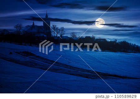 church in the village in winter at night. rural landscape on the snow covered hill in full moon light church in the village in winter at night. rural landscape on the snow covered hill in full moon light 110589629