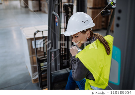Female warehouse worker driving forklift. Warehouse worker preparing products for shipmennt, delivery, checking stock in warehouse. 110589654