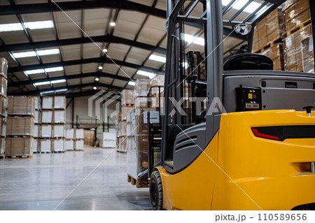Back view of forklift in warehouse in the middle of stored goods.. Forklift driver preparing products for shipmennt, delivery, checking stock in warehouse. 110589656