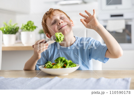 A cute little boy is eating broccoli for lunch and he likes it very much A cute little boy is eating broccoli for lunch and he likes it very much 110590178