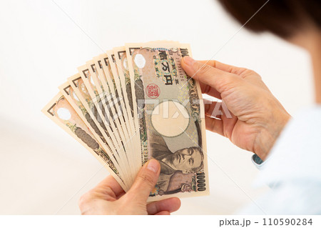 お札を数えるミドル女性の手元 110590284