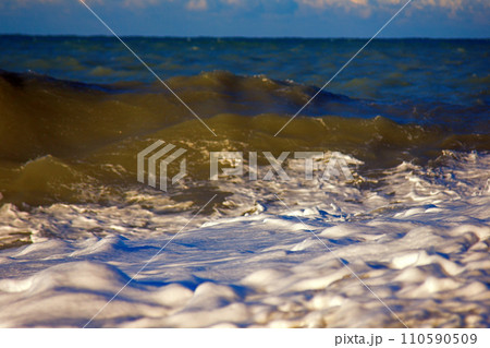 Sea rolling and receding water in rays of setting sun. Sea rolling and receding water in rays of setting sun. 110590509